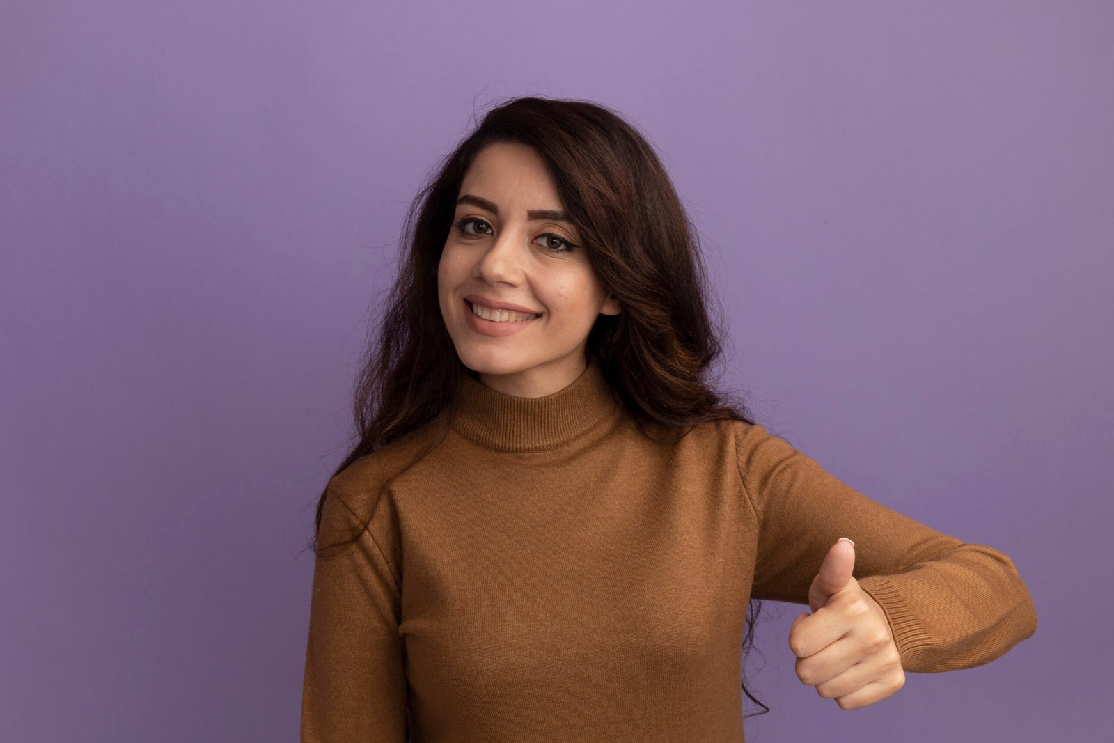 smiling young beautiful girl wearing brown turtleneck sweater showing thumb up isolated on purple background